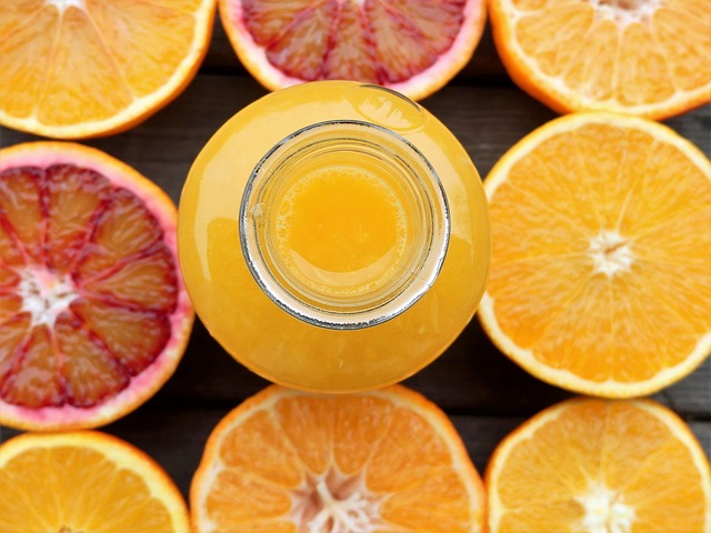 fresh juice splash with oranges greens and yellow fruit around bottle